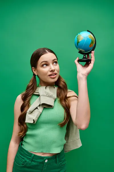 Eine junge Frau in ihren Zwanzigern hält einen kleinen Globus in der Hand und betrachtet die Schönheit und Komplexität der Welt. — Stockfoto