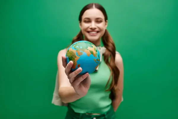 Une jeune femme d'une vingtaine d'années tient délicatement un petit globe dans ses mains, symbolisant les soins, l'unité et la connexion mondiale. — Photo de stock