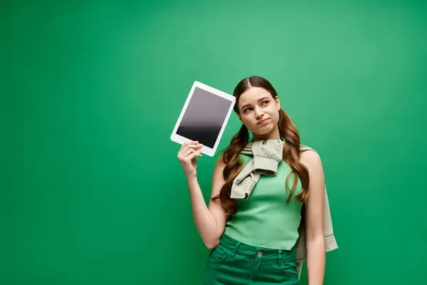 Una joven y hermosa mujer de unos 20 años sostiene con confianza una tableta, dedicada a la comunicación digital. - foto de stock
