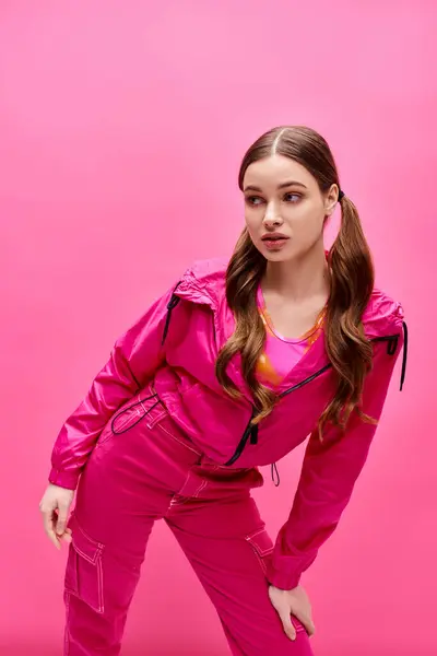 A young, stylish woman in her 20s is posing gracefully in front of a pink background. — Stock Photo