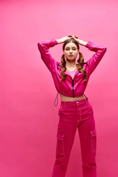 A woman in a pink outfit strikes a pose in a stylish studio setting with a pink background. — Stock Photo