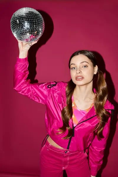 Uma jovem, mulher elegante em seus 20 anos vestindo uma roupa rosa detém uma bola de discoteca deslumbrante, pronto para dançar a noite toda. — Fotografia de Stock