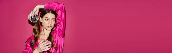 Молода жінка в 20 років, одягнена в стильну рожеву сукню, витончено стоїть на яскравому рожевому тлі. — стокове фото