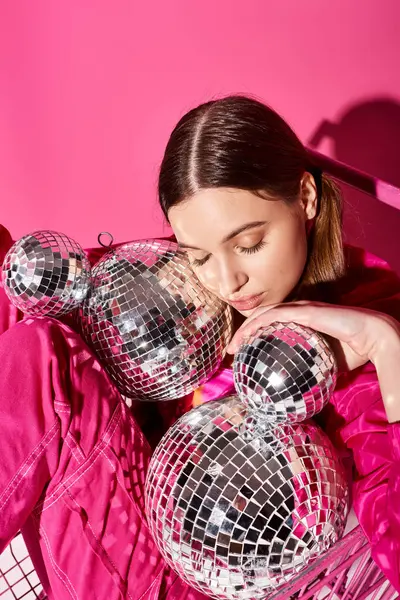 A young, stylish woman in her 20s laying on a bed beside a shimmering mirror ball, creating a dreamy and magical atmosphere. — Stock Photo
