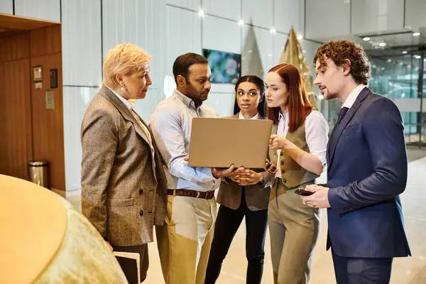 Diverse business team gathered around laptop, brainstorming and collaborating. — Stock Photo