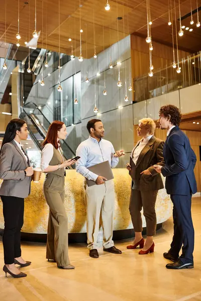A diverse group of business people stand together in a modern lobby. — Stock Photo