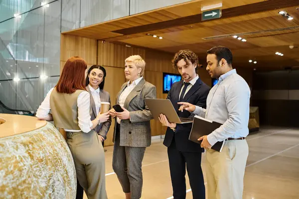 Diverse group of business professionals gathered around laptop discussing strategy. — Stock Photo