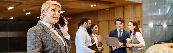 Une femme parlant sur un téléphone portable devant un groupe de personnes. — Photo de stock