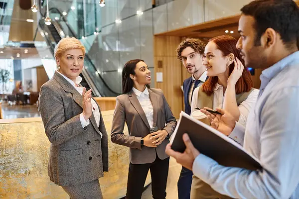 Business professionals of various ethnicities collaborate in a bustling lobby. — Stock Photo
