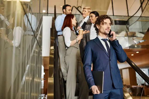 A man in a suit, of an interracial group of business people, talks on a cell phone. — Stock Photo