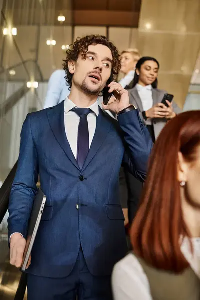 Un uomo in giacca e cravatta si impegna in una telefonata accanto ai suoi colleghi. — Foto stock