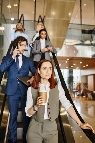 A woman gracefully ascends an escalator, clutching a coffee cup. — Stock Photo