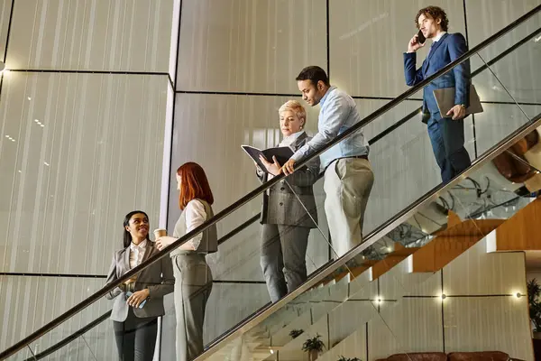 Multicultural business professionals walking down staircase together. — Stock Photo