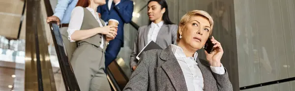 A woman multitasks, talking on a cell phone while walking down an escalator. — Stock Photo