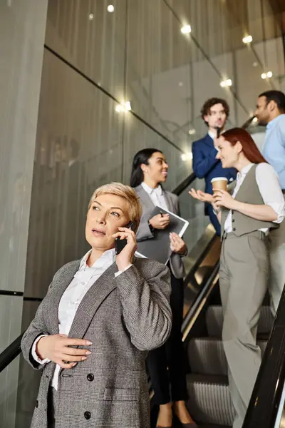 A woman multitasks on an escalator, talking on a cell phone. — Stock Photo