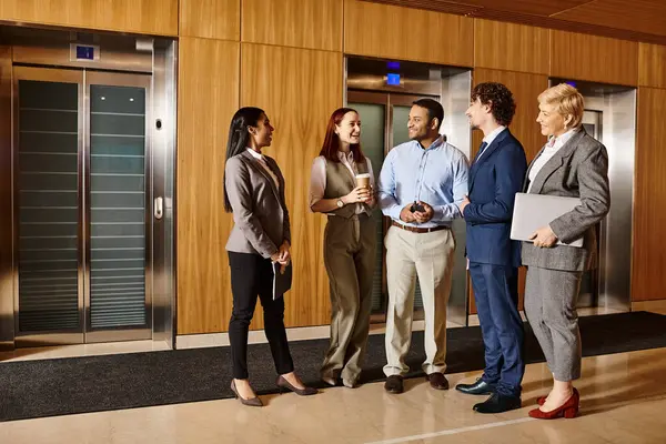 Un grupo multiétnico de empresarios de pie frente a un ascensor, listos para moverse. - foto de stock