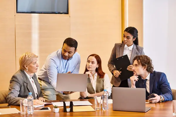 Diverse group of business professionals working on laptops at a table. — Stock Photo