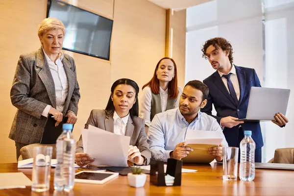 Diverse businesspeople of different races standing around a conference table, discussing ideas. — Stock Photo
