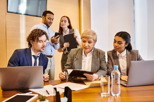 Profissionais diversos com laptops colaborando em uma mesa. — Fotografia de Stock