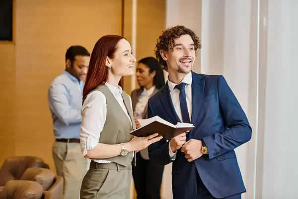 Un hombre y una mujer están de pie como un hombre sostiene un libro delante de ellos. — Stock Photo