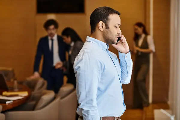 Ein Mann spricht auf einem Handy, während er in einem stilvollen Wohnzimmer steht. — Stockfoto