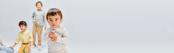 A diverse group of children, stand next to each other in a studio on a grey background. — Stock Photo