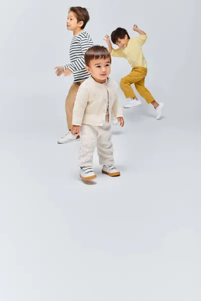 Eine Gruppe kleiner Kinder steht dicht an dicht in einem Atelier vor grauem Hintergrund. — Stockfoto