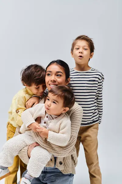 A young Asian mother and her children strike a pose in a studio against a grey backdrop. — Stock Photo