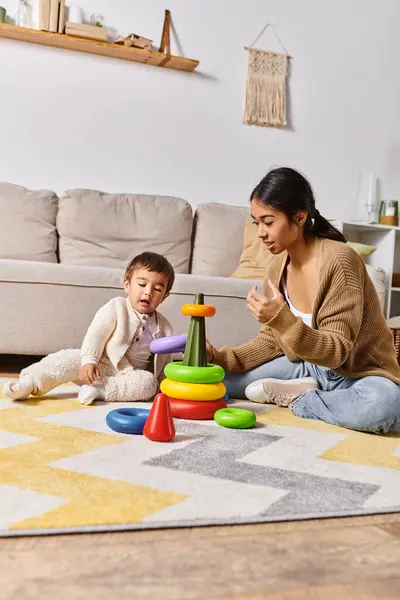 A young Asian mother happily engages with her little son on the living room floor, playing and laughing together. — Stock Photo