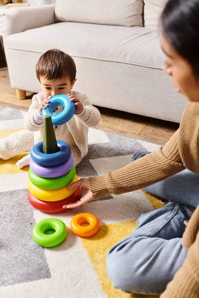 A young Asian mother engaging with her little son on the floor of their cozy living room, sharing moments of joy and connection. — Stock Photo