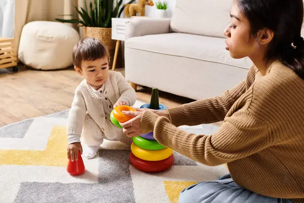 A young Asian mother and her little son play happily on the living room floor. — Stock Photo