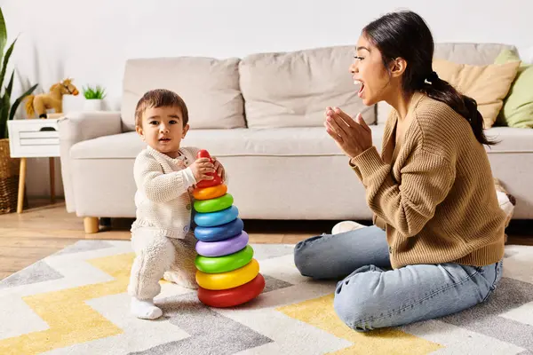 Молода азіатська мати радісно взаємодіє зі своїм маленьким сином на підлозі їх затишної вітальні. — стокове фото