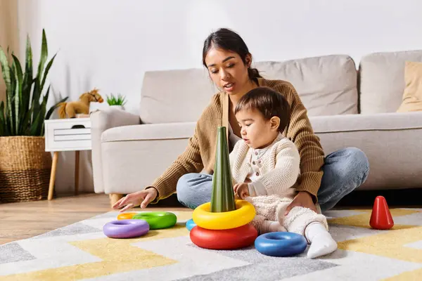 A young Asian mother joyfully plays with her little son on the floor of their living room. — Stock Photo