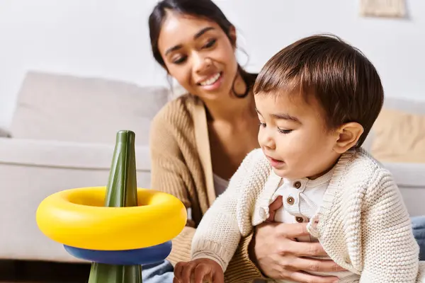 Una giovane madre asiatica gioca con il suo piccolo figlio sul pavimento nel loro salotto, condividendo momenti preziosi insieme. — Foto stock