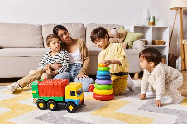 Una joven madre asiática y sus hijos pequeños participan en el juego, riendo y explorando juguetes en su acogedora sala de estar. - foto de stock