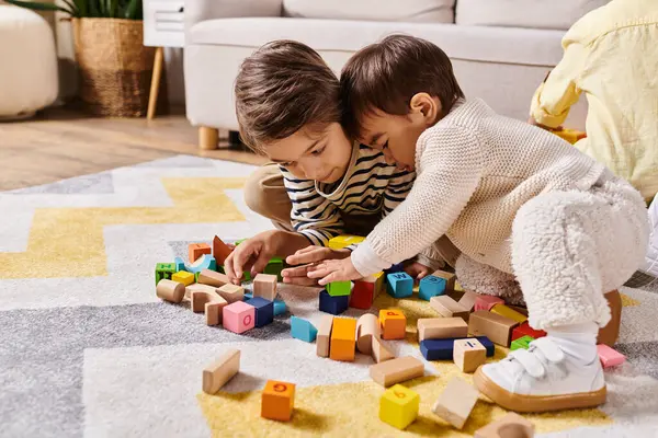 Jeunes garçons construisant avec enthousiasme des structures avec des blocs colorés sur le plancher du salon. — Photo de stock