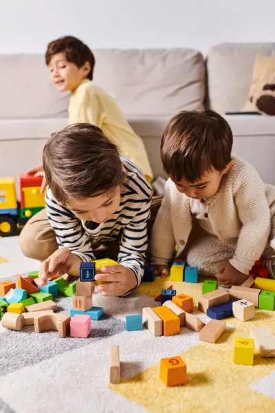 Dos niños, felizmente jugar y construir con bloques de madera en el suelo de su acogedora sala de estar. - foto de stock