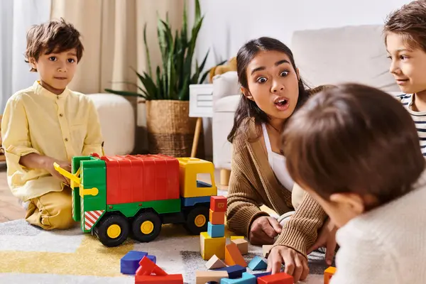 Un groupe d'enfants, dont une jeune mère asiatique et ses fils, jouent joyeusement avec des jouets sur le sol dans un salon confortable. — Photo de stock