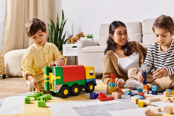 A young Asian mother and her two little sons engage in creative play with wooden blocks in their cozy living room. — Stock Photo