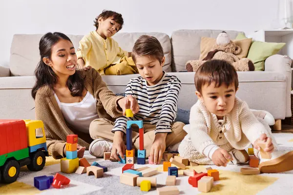 Un grupo de niños, incluyendo una joven madre asiática y sus hijos, jugando felizmente con juguetes en el suelo en una acogedora sala de estar. - foto de stock
