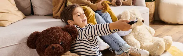 A young boy with a remote control, sitting comfortably on a couch in a living room. — Stock Photo