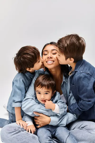 A young Asian mother is sitting on the ground with her children, all wearing denim clothes, creating a close bond. — Stock Photo