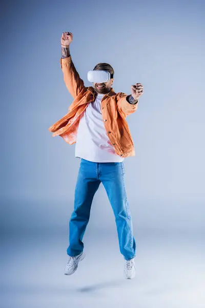 Чоловік, одягнений в гарнітуру VR, радісно стрибає в повітрі в межах студійної обстановки, навушники. — стокове фото