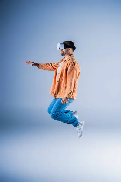 A man in an orange jacket and blue pants is soaring through the air. — Stock Photo
