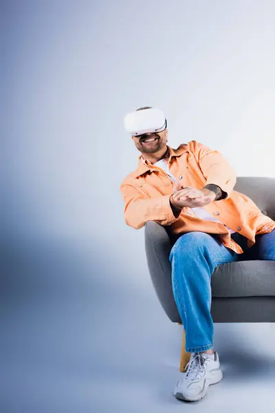Un homme heureux portant un casque VR est assis sur une chaise dans un cadre de studio. — Photo de stock