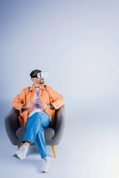 A man in a VR headset comfortably lounging in a chair in a studio setting. — Stock Photo