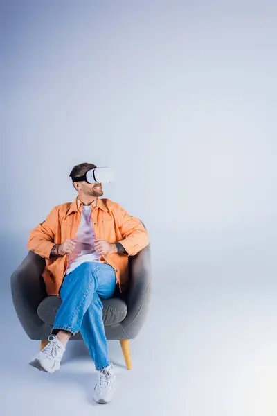 Un uomo in cuffia VR comodamente sdraiato su una sedia in un ambiente da studio. — Stock Photo