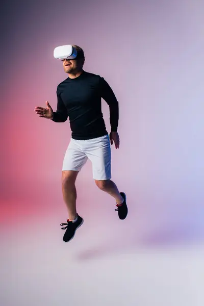 Um homem de camisa preta e calções brancos salta graciosamente no ar, exalando energia e liberdade em um estúdio. — Fotografia de Stock