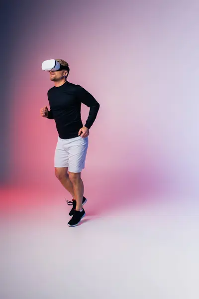 Un hombre con una camisa negra y pantalones cortos blancos se mueve con gracia en un entorno de estudio, la realidad virtual - foto de stock