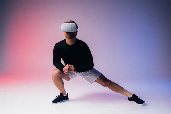 Мужчина в черной рубашке и белых шортах уверенно стоит в студии в наушниках VR, обнимая цифровой мир. — стоковое фото